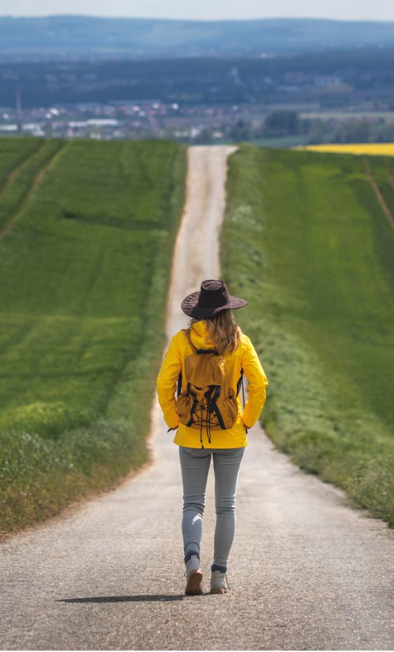 Woman in a yellow jacket walking along a country path